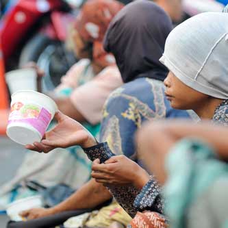 Women sitting in a row, begging, cup held out