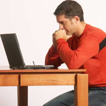 man looking at computer, sitting at table