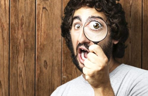 man looking through magnifying glass