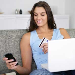 Girl wearing jeans sitting on lounge with mobile phone and laptop