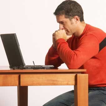 man looking at computer, sitting at table