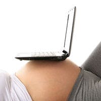 Pregnant woman with laptop balanced on her tummy