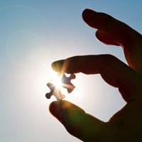 Person holds puzzle piece up to the sun