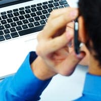 Man on a mobile phone at his computer