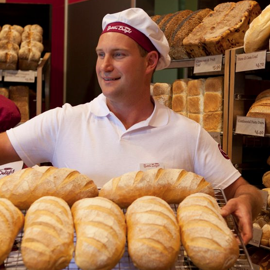 Bakers Delight employee holding up tray of bread