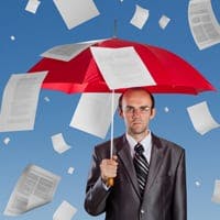 Man under umbrella as papers fall around him