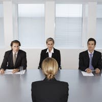 woman in a job interview, sitting face-to-face with three interviewers