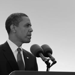 Barack Obama, standing in front of microphones