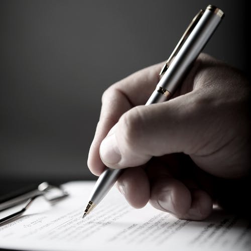Hand holding a pen over a document