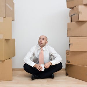 Man sitting between two towers of boxes