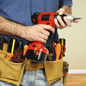 Handyman holding a drill, and wearing toolbelt