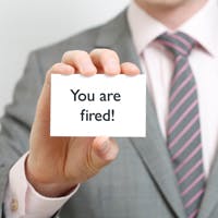 Man holding up "You are Fired" business card
