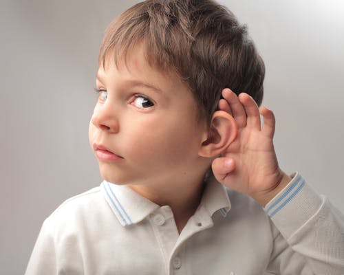 little boy holding his ear listening