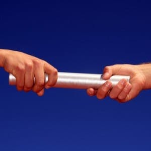 Two hands passing a silver baton