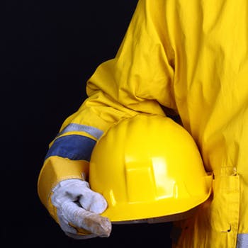 Man dressed in safety gear, holding a hard hat