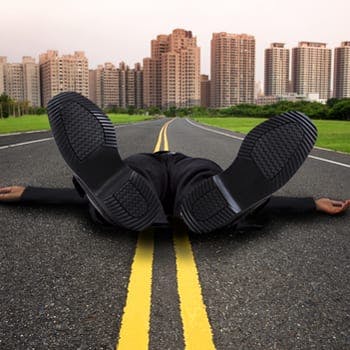 Businessman lying flat on his back on road