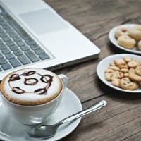 cappucino and biscuits next to computer