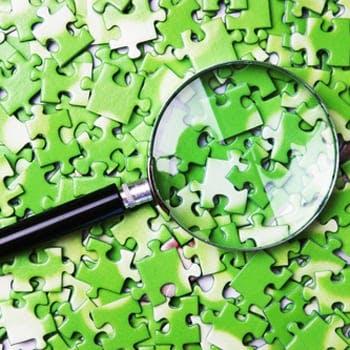 Magnifying glass over green puzzle pieces