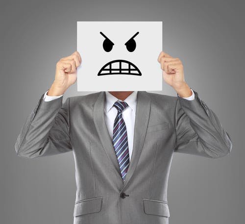 businessman holding angry face sign in front of him